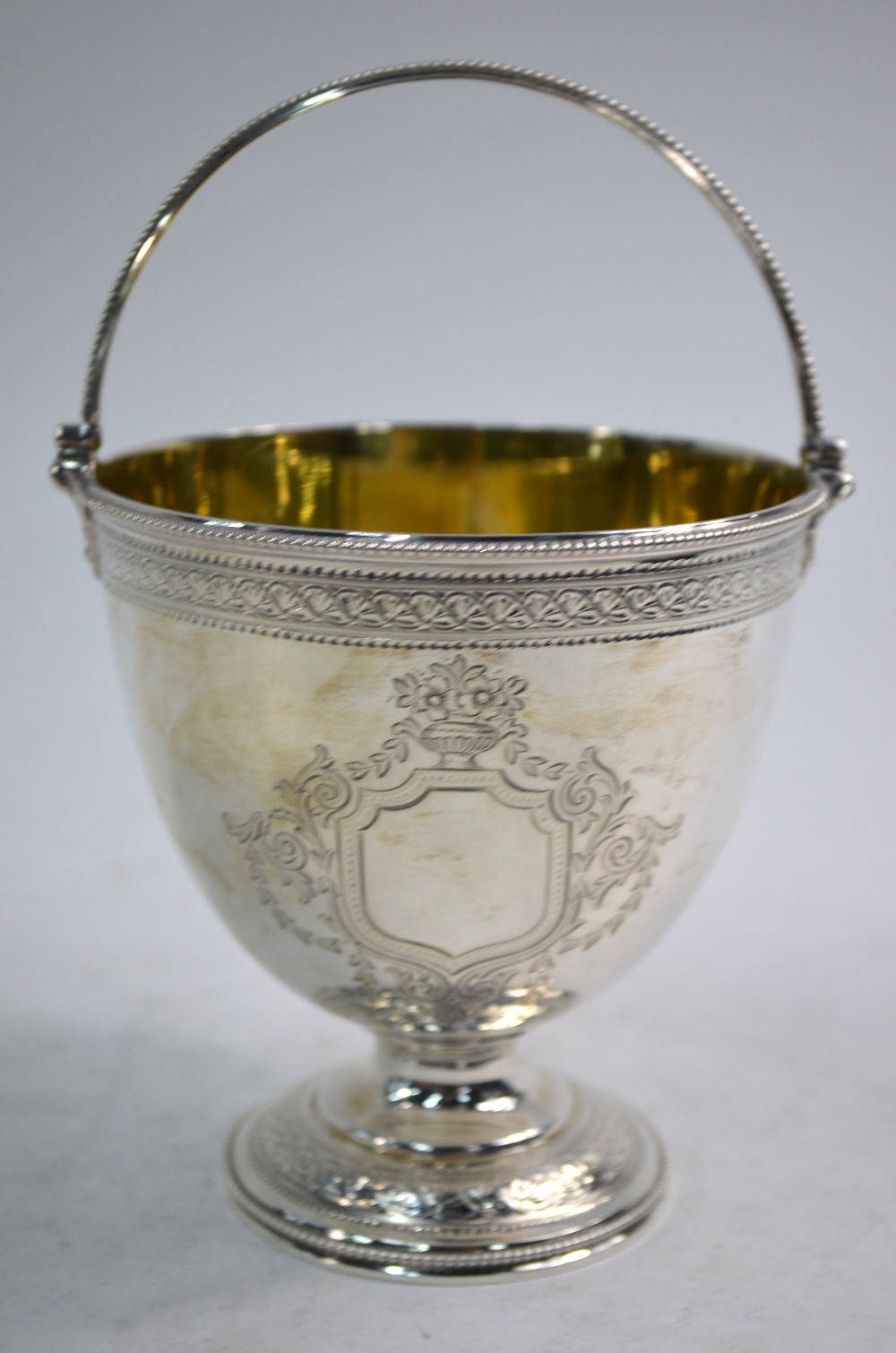 A Victorian ovoid silver bonbon basket with beaded swing handle and stemmed foot,