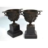 A pair of brown patinated bronze garniture urns, cast with fruiting ivy, on slate bases,