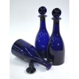 A set of three 19th century Bristol blue glass taper decanters with target stoppers with vestiges