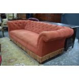 A button upholstered Chesterfield sofa raised on turned mahogany legs to ceramic castors,