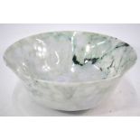 A large jadeite or mottled green stone bowl on circular foot;