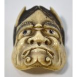 A stained ivory or stag antler netsuke carved as a Hannya mask from the Noh Theatre,