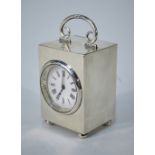 A late Victorian silver boudoir clock with hinged handle, enamel dial and bun feet,
