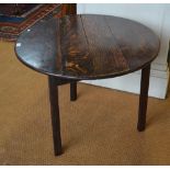 An 18th century oak cricket table, the circular plank top raised on square supports,