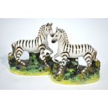 A pair of Staffordshire models of zebras decorated with gold resist stripes,