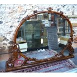 A late 19th century carved walnut framed overmantle of ovoid/arched form,