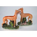 A pair of Victorian Staffordshire flatbacks in the form of standing greyhounds with rabbits on an