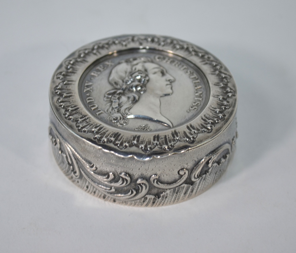 A French circular white metal snuff box, the hinged cover inset with a 1745 Louis XV medallion,