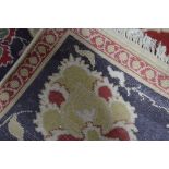 An Indian Agra carpet with large rosettes and scrolling tendril on red ground,