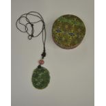 An oval pierced and carved jade pendant suspended from black silk knot work with pink stone and