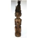 A large African tribal carved wood seated figure with hair top-knot,