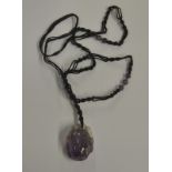 An amethyst carved pendant of leaf and fruit design on macrame chain with amethyst beads
