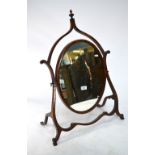A 19th century table top easel dressing mirror, the oval swing plate with a shaped easel frame,