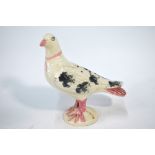 A 19th century pottery model of a dove with hat pin holes, raised on a circular base,