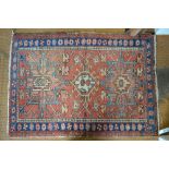 Small red ground Heriz rug with geometric design and rosette border,
