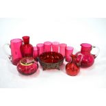 A collection of cranberry glass comprising six small tumblers, vinegar bottle, two milk jugs, vase,