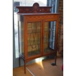 A Sheraton style inlaid mahogany display cabinet with two doors enclosing glass shelves raised on
