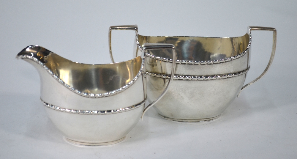 An Edwardian silver oval milk and sugar pair with floral-moulded rims, Haseler Brothers,