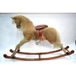A large German flock rocking horse with horsehair mane and tail to/w a leather saddle and stirrups,
