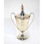 A silver Adam-style urn-shaped trophy cup and cover with twin reeded handles, on stemmed foot,