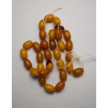 Thirty-one various butterscotch coloured oval beads threaded onto string