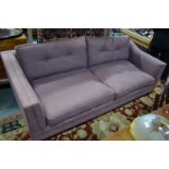 A contemporary three seat sofa in linen mix lavender fabric with buttoned back cushions,