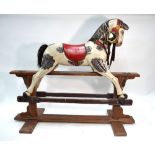 A traditional vintage carved wood rocking horse on safety stand,