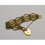 A 9ct seven row gate style bracelet, on 9ct yellow gold padlock fitted with safety chain,