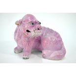 A Chinese mottled pink glazed model of a seated mythological animal,