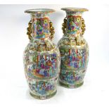 A pair of Chinese Canton famille rose vases; each one with a foliate rim and gilded handles;