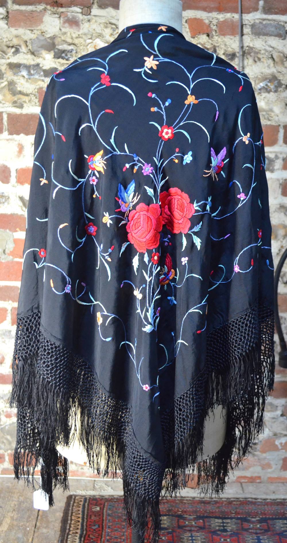 A Chinese silk black ground shawl, decorated with butterflies,