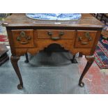 An 18th century oak lowboy with three frieze drawers within an arched apron,
