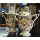 A matched pair of Dresden style porcelain gilded urns profusely floral encrusted with flowers and