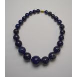 A row of large graduated lapis lazuli beads, graduating from approx 3 cm down to 1.
