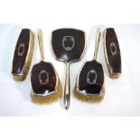 An Art Deco style silver, tortoiseshell and pique-work five-piece brush set with hand-mirror,