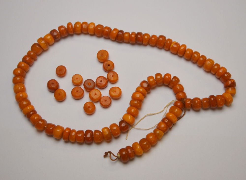 A row of pressed amber beads, and a quantity of loose beads,