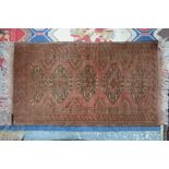 A small Afghan rug, pale red ground,