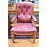 An oversized Victorian oak framed buttoned red leather library armchair on turned front legs to