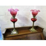 Pair of cranberry oil lamps, brass column base.