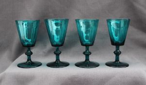 A set of four 19th century green glass wine glasses with tapering bowls on a knopped stem and