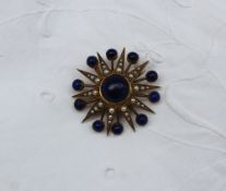 A lapis lazuli and seed pearl brooch of star form, set with a central cabochon lapis lazuli bead,