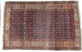 A Caucasian type rug with a central red ground with repeating geometric patterns,