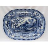 A 19th century blue and white pottery meat plate, decorated to the centre with a fortified town,