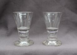 A pair of 18th century shot glasses with a tapering bowl, air bubble stem and spreading foot,