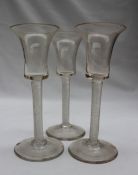 A set of three 18th century wine glasses with a trumpet shaped bowl on a tight air twist stem and