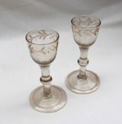 A pair of 18th century wine glasses with a leaf and flower engraved rim on a balustroid stem,