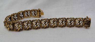 A yellow metal bracelet with rectangular pierced scrolling links,