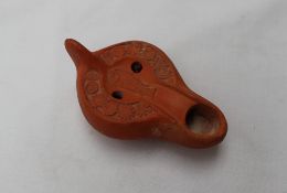 A Roman terracotta oil lamp, moulded with fish and flower heads,