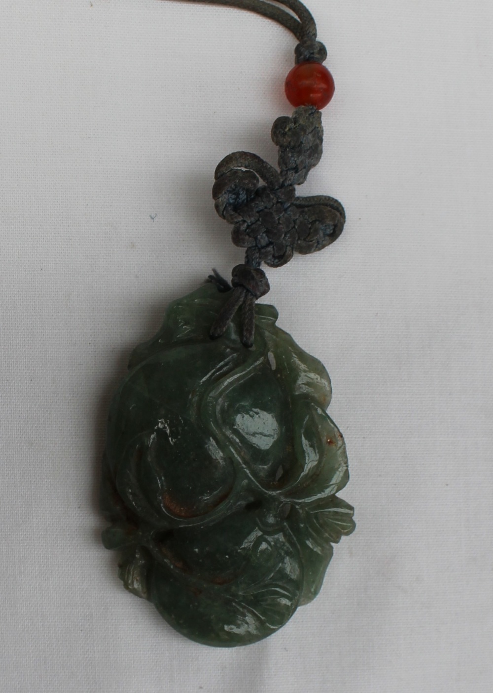 A carved jade pendant in the form of fruit and leaves on a cord necklace 55mm x 35mm