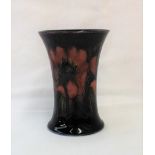 A Moorcroft pottery vase of flared form decorated with flambe anenome to a blue ground,